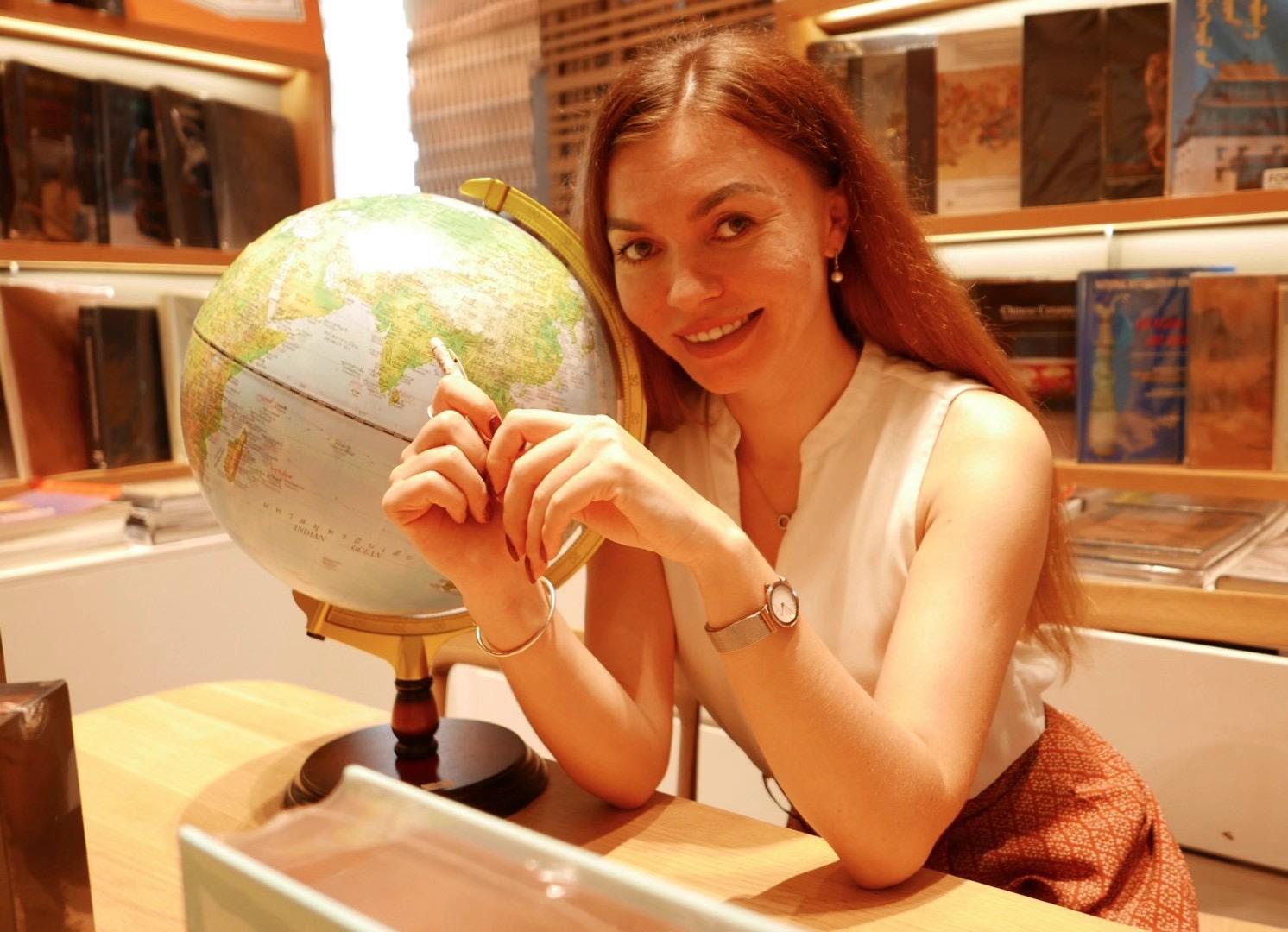 Alisa smiling at her desk with a globe, in a bookshop
