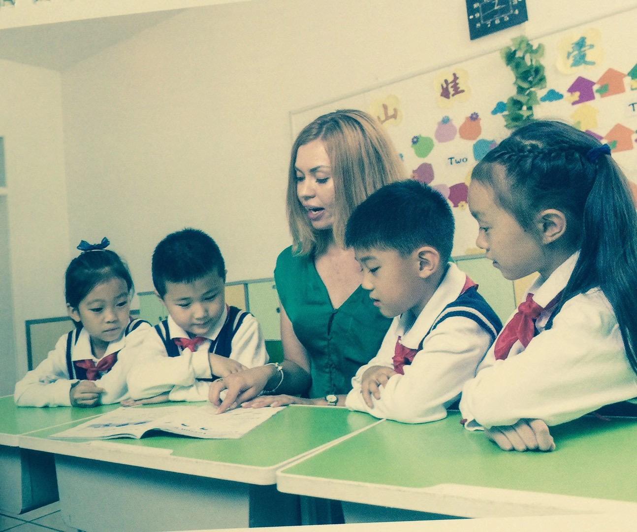 Alisa teaching two young students at a classroom desk