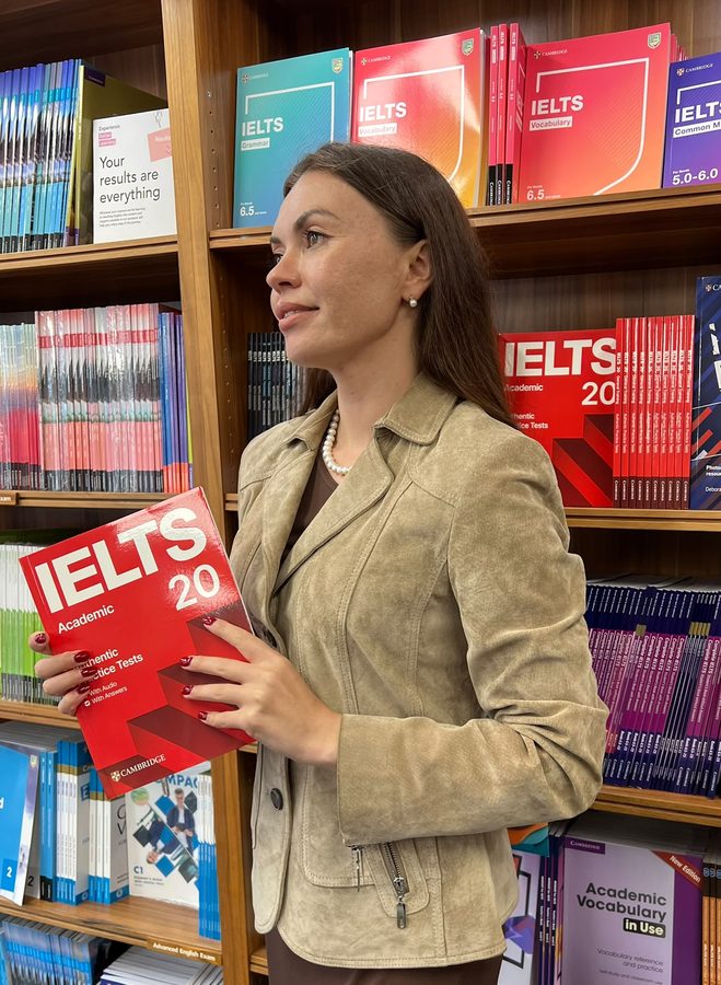 Alisa holding an IELTS preparation book in a bookshop